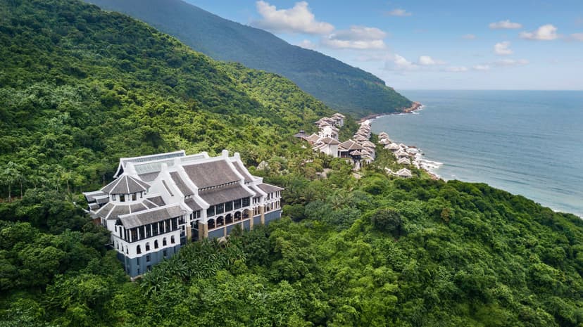 Hero/establishing shot of InterContinental Danang Sun Peninsula Resort, Da Nang, Vietnam. A Bill Bensley clifftop masterpiece on a private bay inside the Son Tra Nature Reserve — four levels (Heaven, Sky, Earth, Sea) linked by a funicular, 