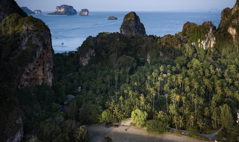 Hero/establishing shot of Rayavadee, Krabi, Thailand. A boat-only castaway icon on the Phra Nang headland in Krabi, ringed by dramatic limestone karsts and three beaches including the legendary Phra Nang.