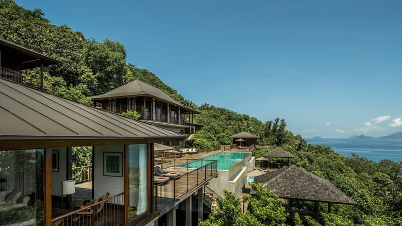Signature hero of Four Seasons Resort Seychelles (Petite Anse, Mahé, Seychelles): the single most iconic wide view — Hillside villas, Private infinity pools, Ultra-luxury. Golden-hour, landscape, room to overlay text.
