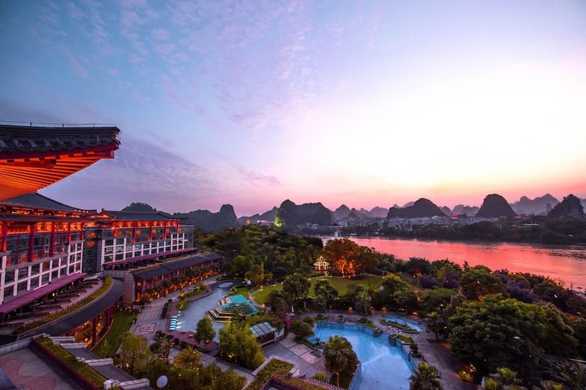 Hero/establishing shot of Shangri-La Guilin, Guilin, China. A riverside garden hotel on the east bank of the Li River, ringed by Guilin’s famous karst mountains — an 11,000-square-metre garden that doubles as a family park, with a Kids Club