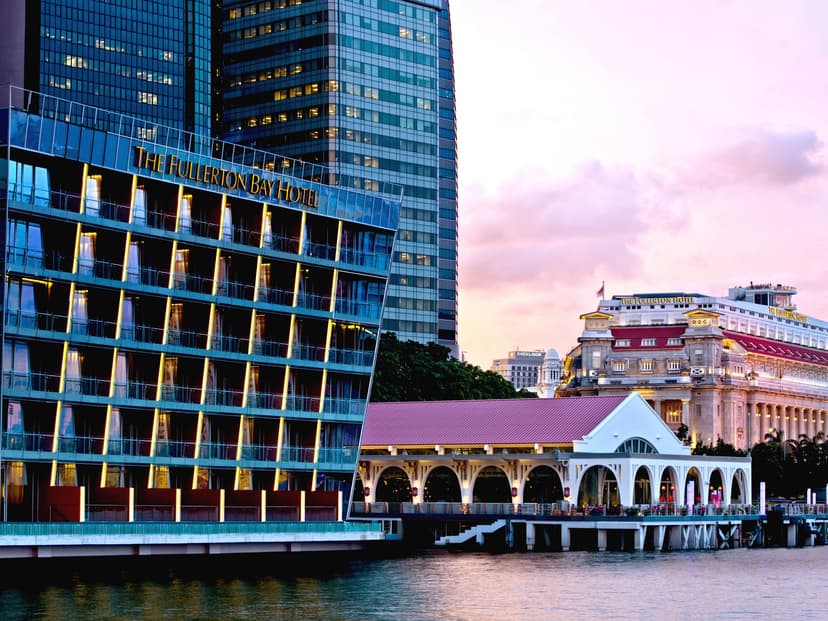 Hero/establishing shot of The Fullerton Bay Hotel Singapore, Singapore. A waterfront design boutique built entirely over water on Marina Bay, entered through the heritage Art Deco Clifford Pier, with 360-degree skyline views and an André Fu