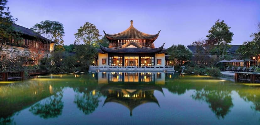 Hero/establishing shot of Four Seasons Hotel Hangzhou at West Lake, Hangzhou, China. A low-rise Jiangnan garden resort on the banks of UNESCO West Lake — acres of lily ponds, bamboo, willows and mist-covered lagoons in Song-Dynasty-garden s