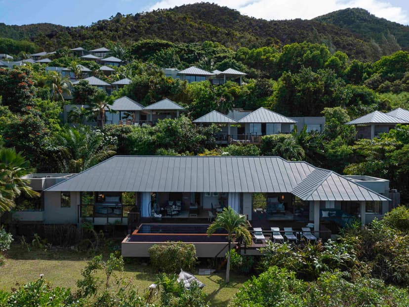 Signature hero of Raffles Seychelles (Praslin, Seychelles): the single most iconic wide view — All-villa resort, Private pools, Raffles butler. Golden-hour, landscape, room to overlay text.