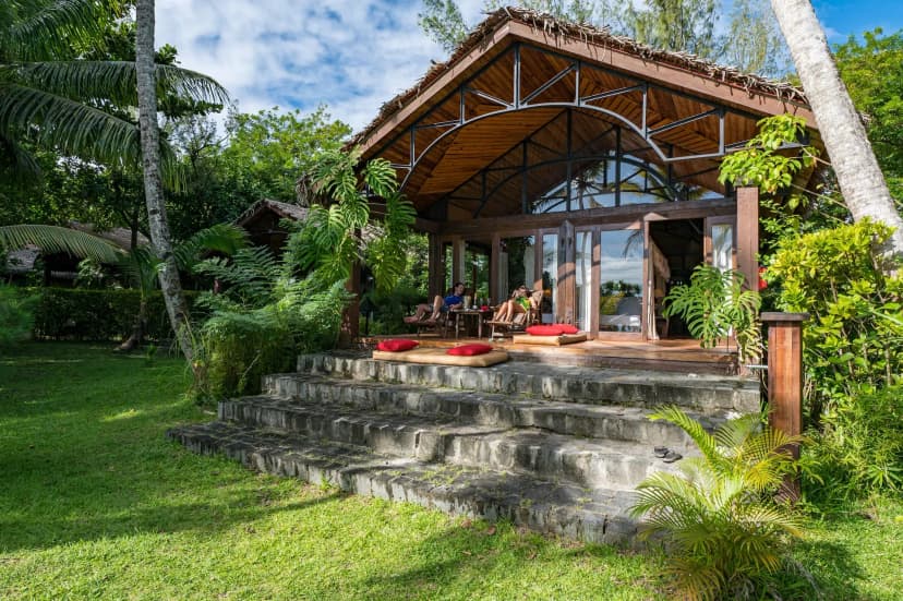 Signature hero of Princesse Bora Lodge & Spa (Île Sainte-Marie, Madagascar): the single most iconic wide view — Whale-watching island, Barefoot eco-lodge, Palm-grove beach. Golden-hour, landscape, room to overlay text.