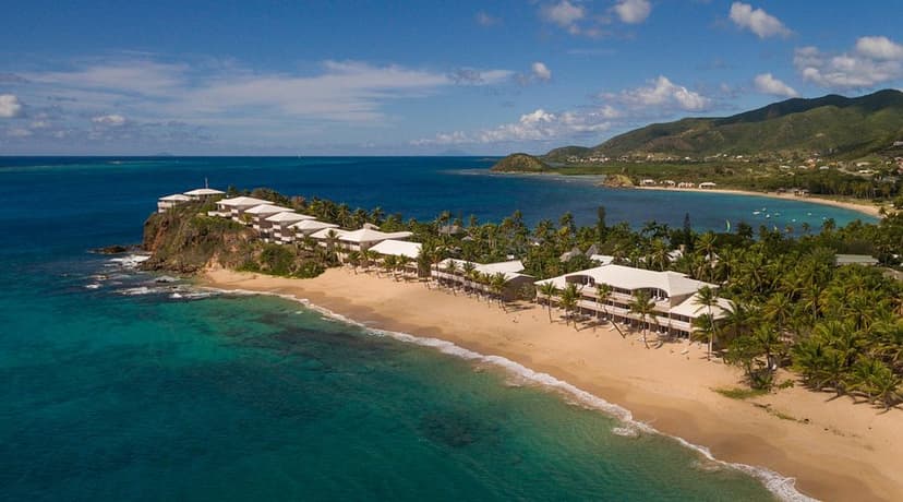 Hero/establishing shot of Curtain Bluff, Antigua. An iconic resort since 1962, set on a bluff between two beaches — calm Bay Beach for swimming and watersports, and the Atlantic Surf Beach.