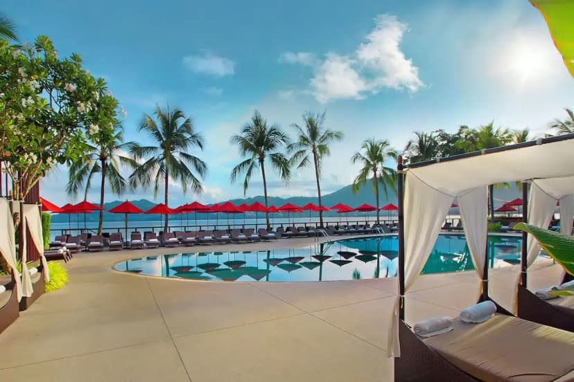 Hero/establishing shot of Amari Phuket, Phuket, Thailand. A beachfront resort on a secluded headland at the southern corner of Patong Beach — a private-beach retreat with three pools, including a clifftop infinity pool over Patong Bay, yet 